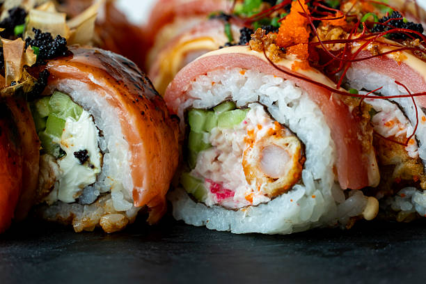 istock Assorted sushi rolls on a black slate board with creamy and crispy toppings, combining textures and colors in an elegant display. 2222598931