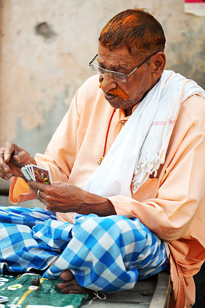 Old man playing cards, Amritsar city, Punjab, India. Amritsar is a city rich in Sikh heritage and history being a major pilgrimage centre, especially for the Golden Temple, but also for Partition in 1947. The Heritage Walk explores its traditional architecture, historic lanes, Katras, Akharas, Bungas, Havelis, and Hattis. The Punjab, is the state which is the heart of India’s Sikh community, bordering Pakistan. The city of Amritsar is best known for Harmandir Sahib, the holiest gurdwara, or Sikh place of worship and a major pilgrimage site. The distinctive Golden Temple, as it is known in English, is surrounded by the Pool of Nectar.