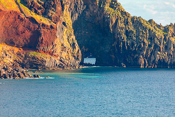 Sao Lourenco peninsula in Madeira, with cliffs and basalt rock formations in the Atlantic Ocean. Azure waters lap against the dark volcanic rock formations. Deep blue ocean meets rugged cliffs