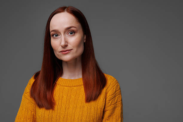 istock Redhead woman in knitted sweater looking at camera isolated on grey 2222602859