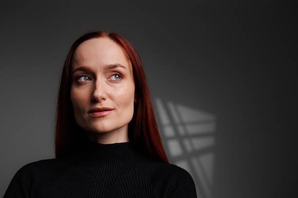 istock Pretty redhead woman looking away on grey background with abstracted shadow 2222603428