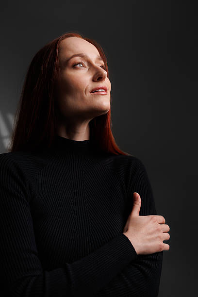 istock Redhead woman in black turtleneck looking away on grey background with shadow 2222603450