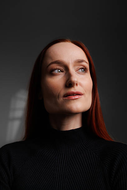 istock Redhead woman in turtleneck posing on grey background with abstracted shadow 2222603452
