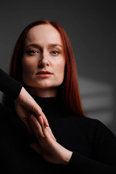 istock Redhead woman in black turtleneck on grey background with abstracted shadow 2222603515