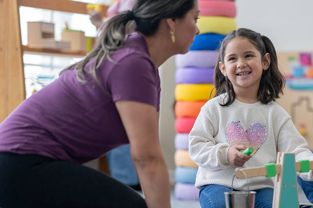 istock Smiling Girl Engaged in Fun Learning Activity with Teacher in Colorful Classroom 2222608910
