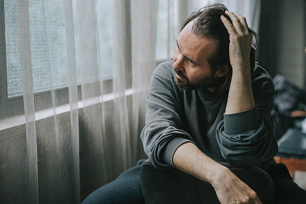 istock Melancholic man sitting by the window lost in thought 2222611747