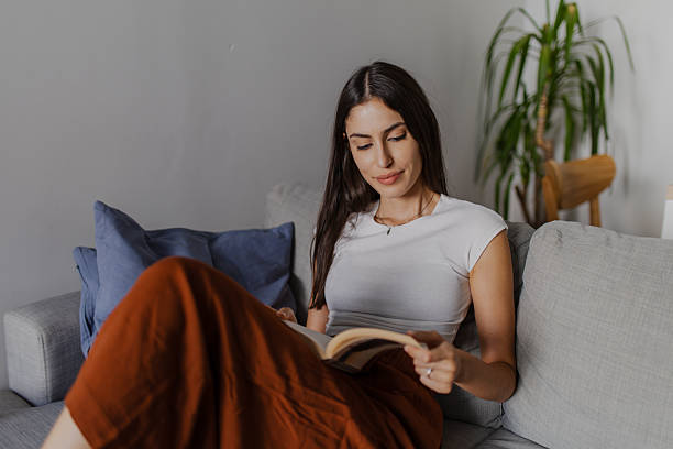 istock Young woman relaxing on sofa reading a book 2222611789