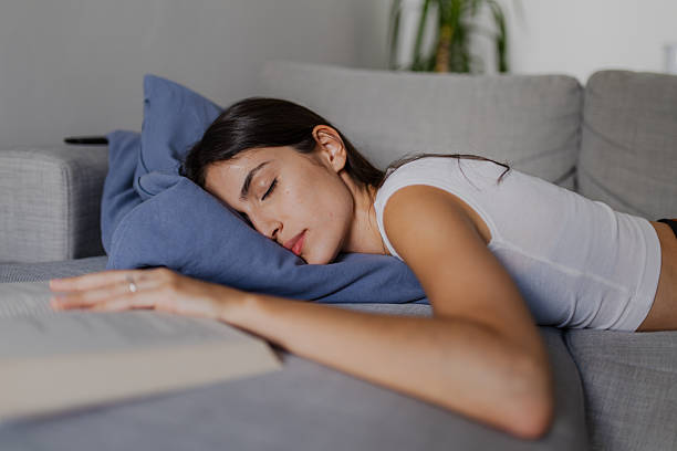 istock Young Woman Sleeping Peacefully on Sofa After Reading a Book 2222611820