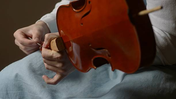 istock Skilled luthier crafting violin, carefully selecting specialized tools and meticulously joining delicate wooden components in traditional workshop setting 2222612894