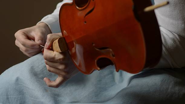 istock Skilled luthier crafting violin, carefully selecting specialized tools and meticulously joining delicate wooden components in traditional workshop setting 2222612897