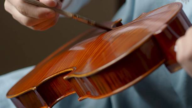 istock Skilled luthier crafting violin, carefully selecting specialized tools and meticulously joining delicate wooden components in traditional workshop setting 2222612900