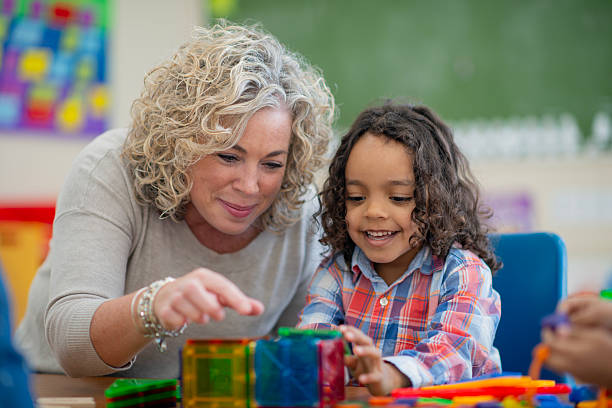 istock Teacher Assisting Child in Classroom with Creative Educational Activity 2222613349