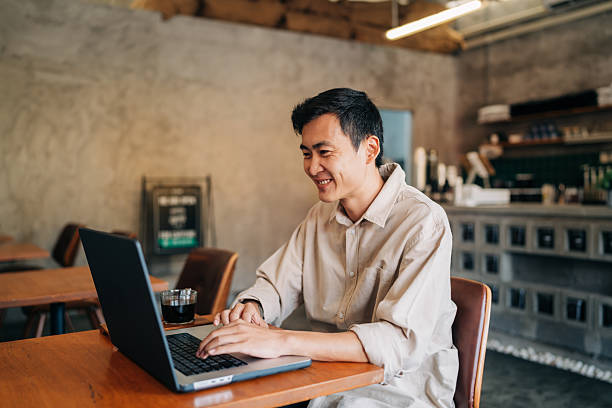 istock Entrepreneur working on laptop at cafe, focused and smiling in casual setting. 2222615137