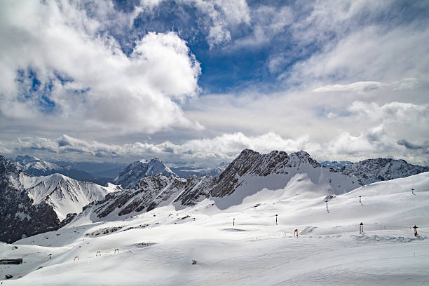 Wide snowy slope with ski lifts and distant peaks