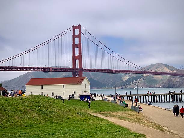 A view of the Golden Gate Bridge, near San Francisco in California, a chain fence in the foreground similar in shape to the bridge's suspension design.