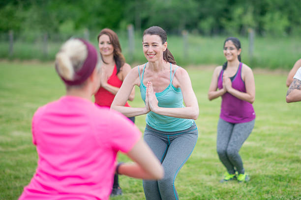 istock Group Fitness Class Practicing Yoga Outdoors on a Sunny Day 2222618395