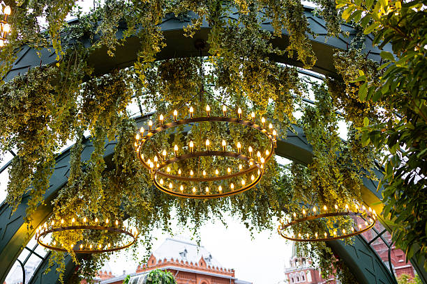 istock A decorative arch decorated with lush greenery and round illuminated chandeliers. 2222625466