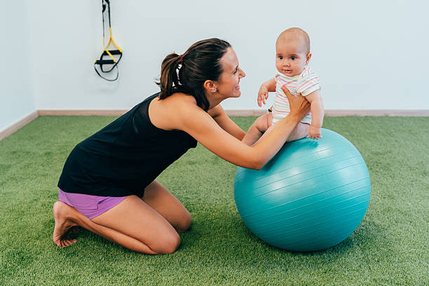 istock Physiotherapist helping baby doing exercises on a pilates ball 2222625474