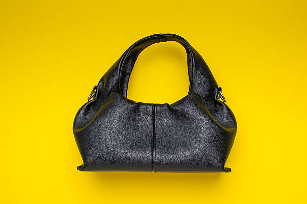 istock Stylish Black Handbag on Vibrant Yellow Background 2222630349