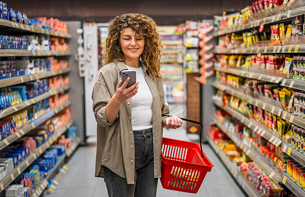 istock Woman using smartphone while grocery shopping in supermarket 2222632406