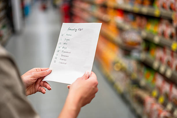 woman holding shopping list in supermarket - diyet listesi stok fotoğraflar ve resimler