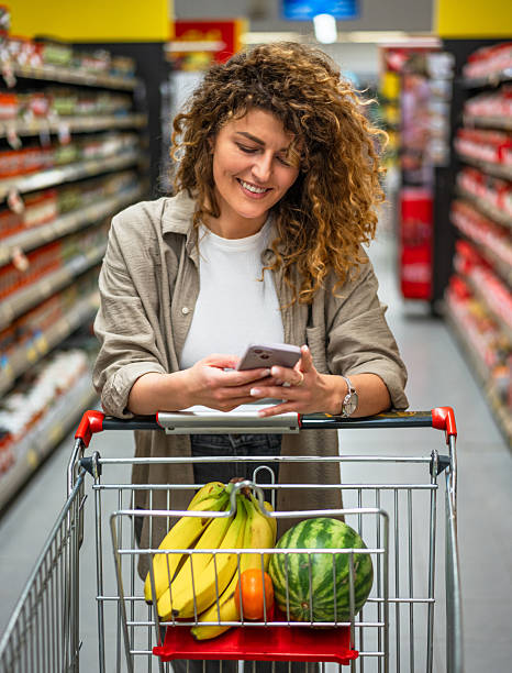 istock Smiling woman using smartphone while shopping in supermarket 2222632888
