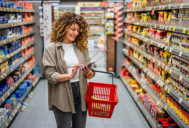 istock Woman using smartphone while grocery shopping in supermarket 2222633178