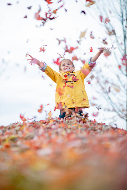 istock Child Enjoying Autumn Leaves Outdoors in a Vibrant Fall Setting 2222634504