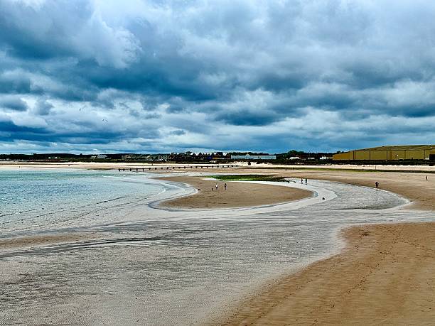 istock Incidental people walking on a beach with dramatic cloudscape overhead at Blyth in Northumberland 2222634652