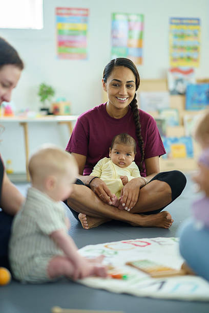 Smiling Woman Holding Baby During Mommy and Me Class in Classroom