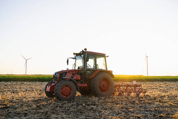 istock Agricultural tractor is working on the field with wind turbines 2222636696