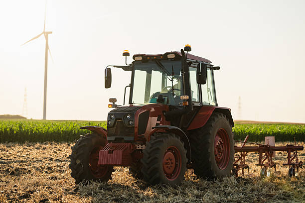 istock Agricultural tractor is working on the field with wind turbines 2222637006