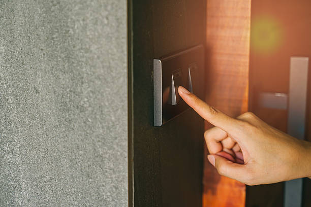 istock Hand Press switch. Finger Touching Modern Light Switch on Stylish Wall with Warm Illumination in Contemporary Interior Design Setting 2222638788