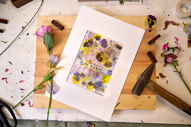 istock Handmade botanical print with 'Be Happy' text, matted and ready for display – floral pigments, hammer, flowers and stamps in creative workspace 2222639604