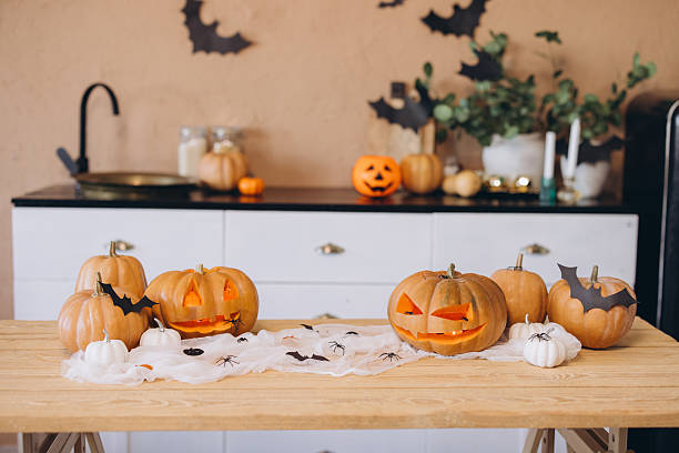 istock Halloween pumpkins and decorations sitting on a wooden table in a kitchen 2222641484