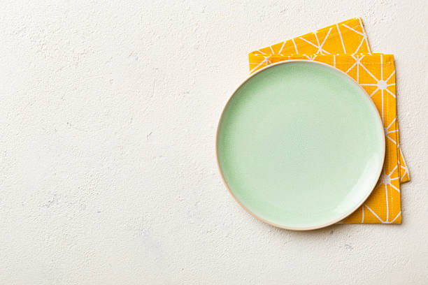 istock Top view on colored background empty round green plate on tablecloth for food. Empty dish on napkin with space for your design 2222642527