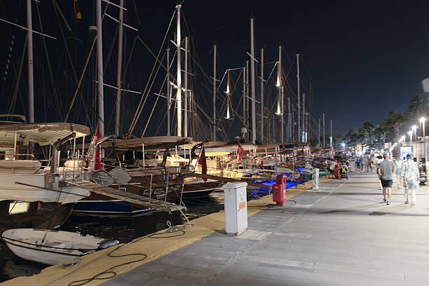 BODRUM, TURKEY - JUNE 29: Wooden yachts and sailing boats are docked along the marina under artificial lighting on June 29, 2025, in Bodrum, Turkey. The evening atmosphere highlights the town’s popular nautical tourism and summer nightlife.