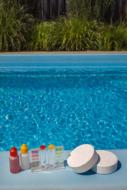 istock Poolside scene with chlorine tablets, water test kit, and reagent bottles used for testing and maintaining proper chemical levels in a backyard swimming pool. 2222647984