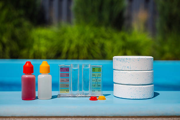 Chlorine tablets and water test kit with dropper bottles and color chart on the pool edge, essential tools for pool maintenance on a sunny summer day. High quality photo