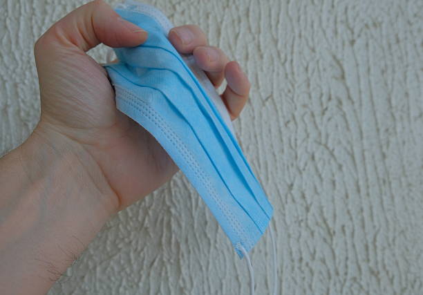 Blue medical mask in human hand on light background 1