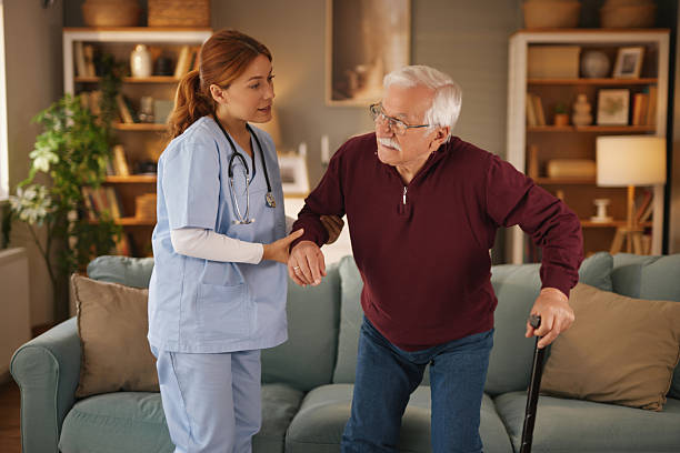 istock Home nurse assisting elderly man getting up from sofa 2222653372