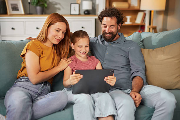 istock Happy family watching tablet together on sofa at home 2222656065