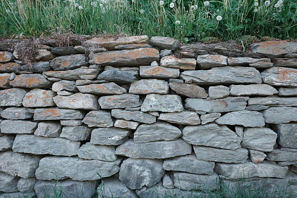 istock Rough, irregular stone wall composed of variously shaped and sized gray stones, tightly fitted together. 2222656151