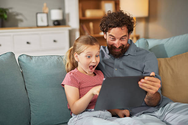 istock Father and daughter sharing a moment of excitement while using a tablet at home 2222656215