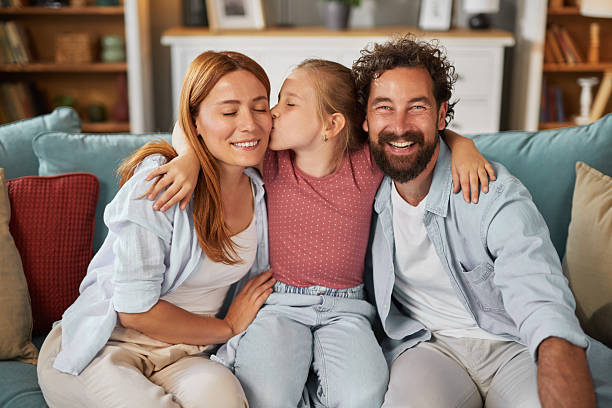 istock Daughter kissing her parents while sitting on sofa at home 2222656833