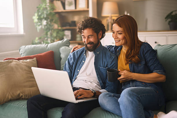 istock Happy couple relaxing on sofa browsing internet on laptop 2222660079