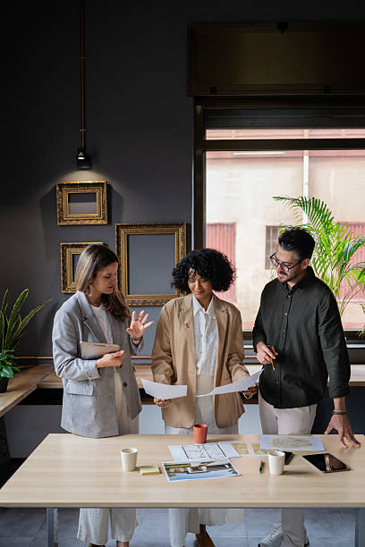 istock Three architects are examining blueprints in a modern office, engaging in a collaborative discussion about the project 2222660218