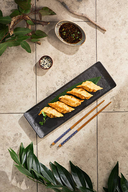 Gedza tempura rustic bright overhead, rectangular black plate with golden dumplings on stone surface