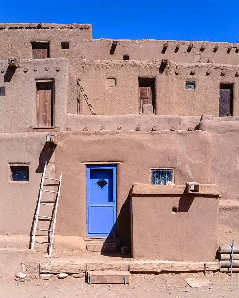 Bell over blue door and framed by adobe wall