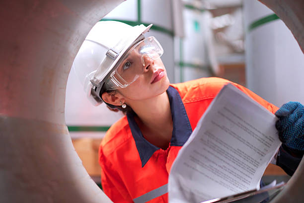 Senior Asian industrial engineer is performing inspection a heavy machines and computer systems in the factory. Senior engineer checks manufacturing production line.